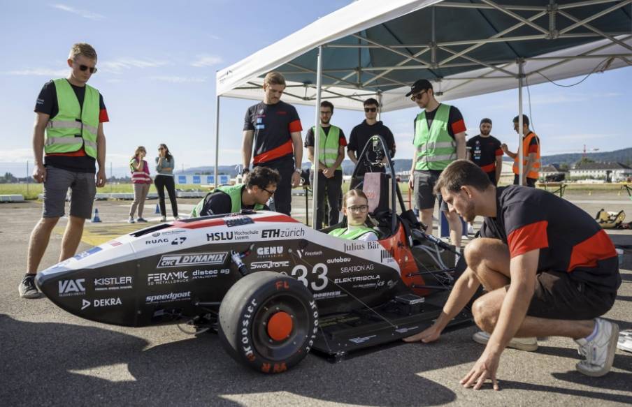 Des étudiants de l'ETH Zurich et de Lucerne à côté d'une voiture de course électrique